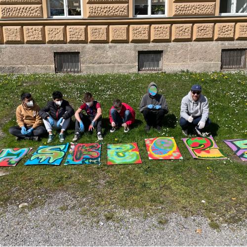 Schüler sitzen hinter den Kunstwerken. 