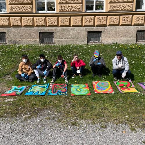 Schüler sitzen hinter den Kunstwerken. 
