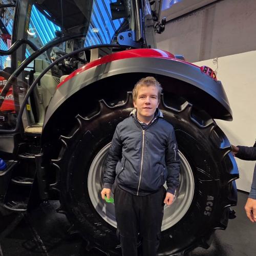 Schüler vor einen Rad eines Traktors zum Größenvergleich