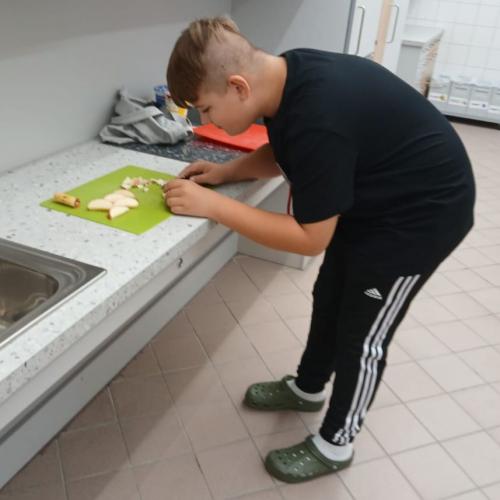 Schüler in der Küche schneidet Äpfel