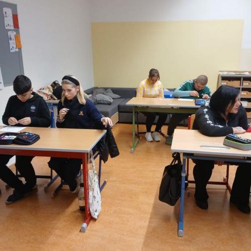 Schüler arbeiten mit Assistentin im Unterricht