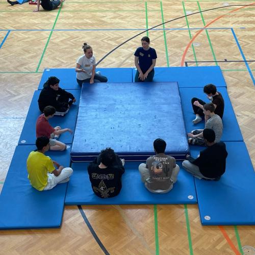 Schüler sitzen um den Weichboden herum. 