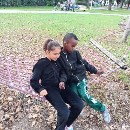 Schüler auf einer Hängematte auf einem Spielplatz
