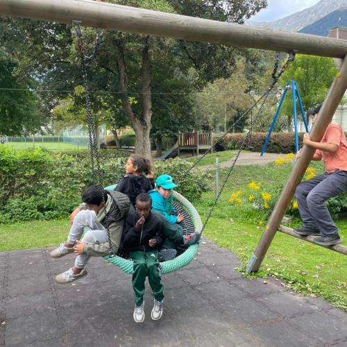 Schüler in einer Nestschaukel auf einem Spielplatz