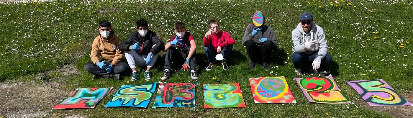Schüler sitzen hinter den Kunstwerken.