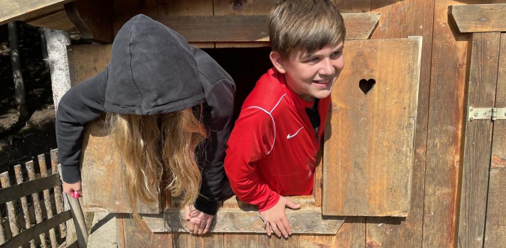 CB Schüler schauen aus dem Fenster eines Holzhauses hinaus.